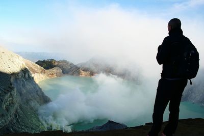 Rear view of hiker looking at ijen against sky