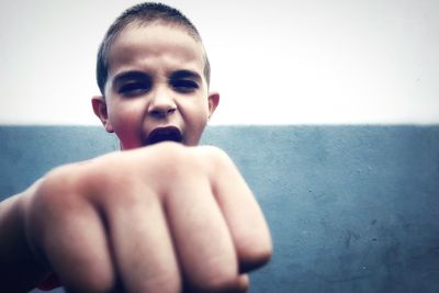 Boy showing fist against wall