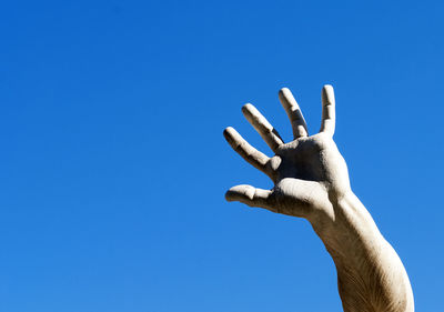 Low angle view of hand against clear blue sky