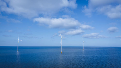 Wind turbines in sea against sky