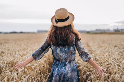 Rear view of woman wearing hat on field