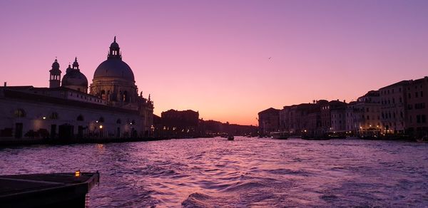 Canal amidst buildings against sky at sunset