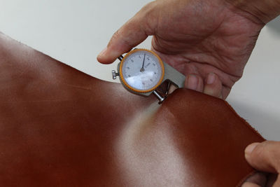 Close-up of hand holding leather thickness gauge
