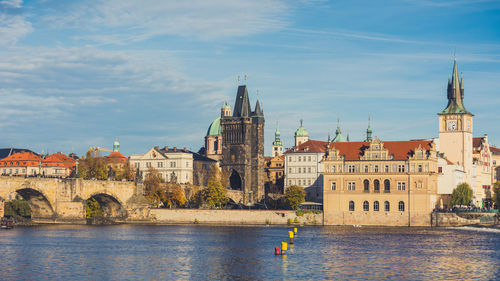 Buildings by river against sky