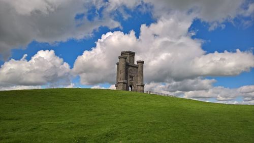 View of grassy field against cloudy sky