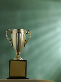 Close-up of trophy on table against green wall
