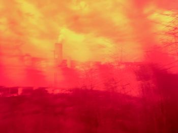 Digital composite image of factory against orange sky