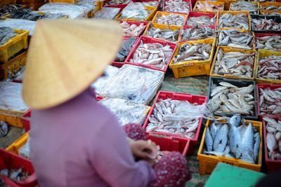 Close-up of person in hat selling fish at market stall