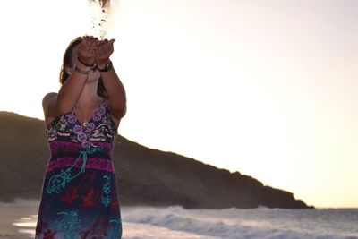 Young woman standing on shore at beach