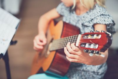 Midsection of girl playing guitar at home