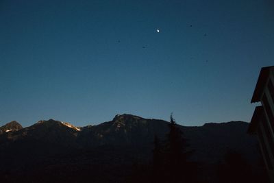 Low angle view of silhouette mountains against clear sky at night