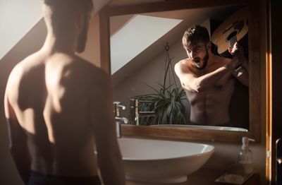 Digital composite image of young shirtless man standing in bathroom