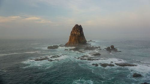 Rock formation in sea against sky