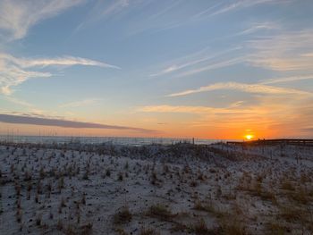 Scenic view of snow covered field against sky during sunset