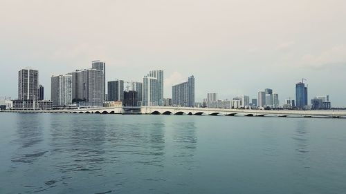 Sea by cityscape against sky