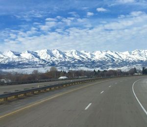 Road by snowcapped mountains against sky