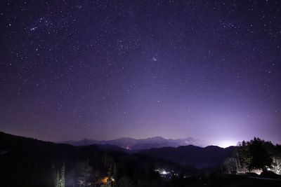 Scenic view of illuminated mountains against star field