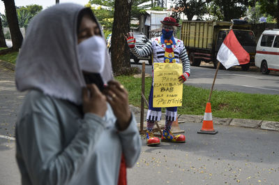 Clown holding banner while standing on street