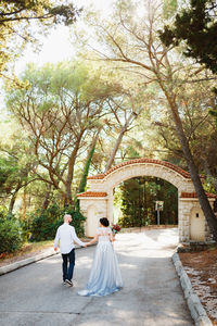 Rear view of couple walking along plants