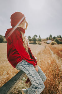 Midsection of woman sitting on field against sky