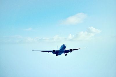 Low angle view of airplane flying against blue sky