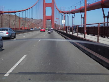 Cars on suspension bridge against sky in city