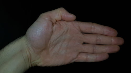 Close-up of human hand against black background