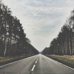 Empty road with trees in background