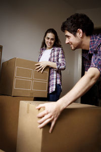 Couple carrying cardboard boxes in new house