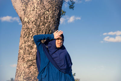 Man standing by tree against sky