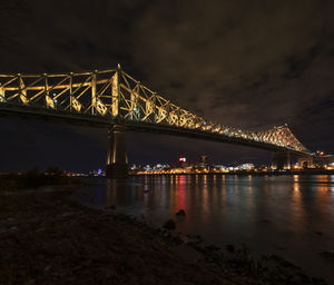 Illuminated bridge over river against sky at night