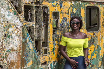 Happy africa woman from ghana stands in front of an old broken helicopter