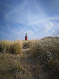 Lighthouse on field against sky