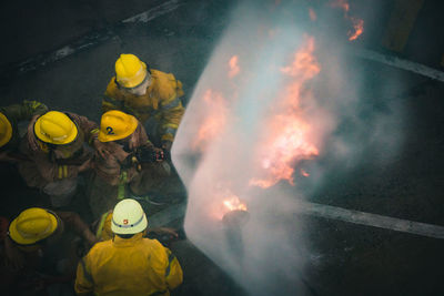 High angle view of firefighters spraying water on fire