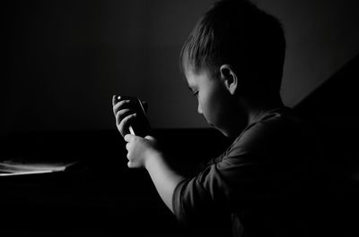 Side view of child playing with smart phone
