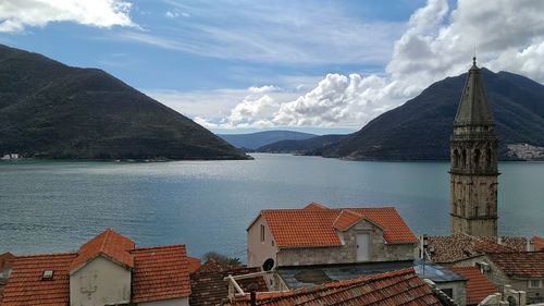 Houses by lake against mountains and sky