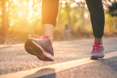 Low section of woman walking over road