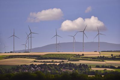 Windmills on field against sky