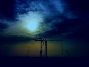 Low angle view of electricity pylon against cloudy sky