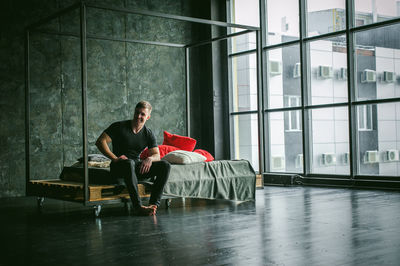 Muscular man sitting on bed at home