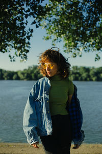 Portrait of young woman standing against trees