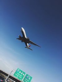 Low angle view of airplane flying against clear blue sky