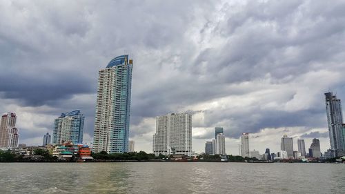 Modern buildings by river against sky