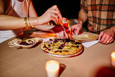 Midsection of couple eating tarts on table