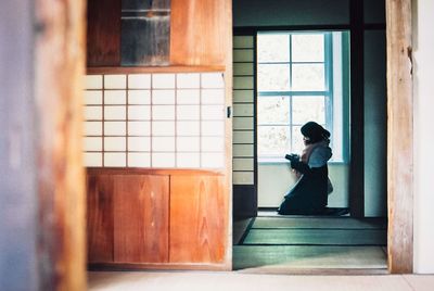 Side view of woman standing by window