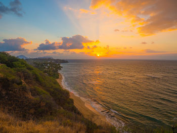 Scenic view of sea against dramatic sky during sunset