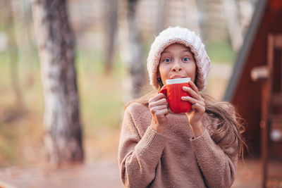 Portrait of woman holding ice cream standing outdoors