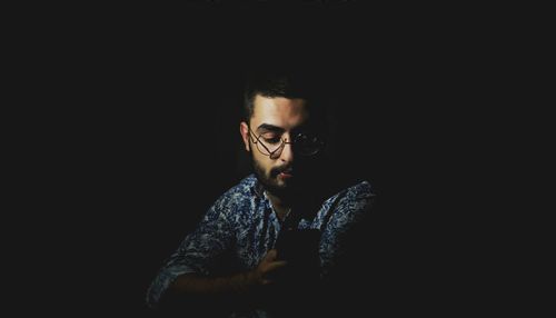 Portrait of young man against black background