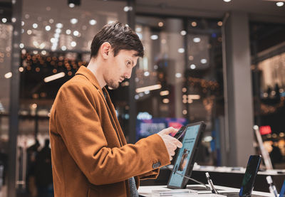 A young man examines a smartphone in a store.