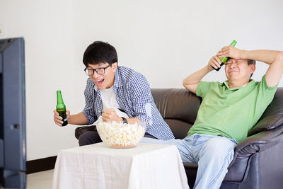 Son clenching fist with father while watching sport at home